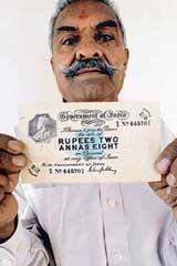 Coins and notes collector Kantilal Nathubai Prajapati poses with a rare two rupees and eight annas note at his residence in Ahmedabad on Wednesday