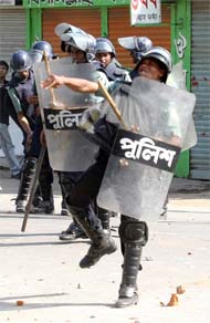 A policeman hurls stones at activists during a general strike in Dhaka on Thursday. Troops and riot police fought pitched battles with protesters as a strike aimed at forcing electoral reforms in Bangladesh turned violent. 