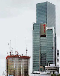 An under-construction building is dwarfed by a highrise tower in Singapore.