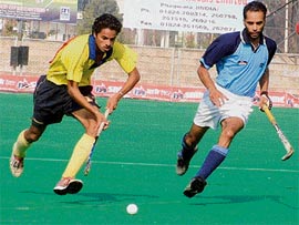 A Punjab & Sind Bank player (yellow) gets past an RCF player during a league match of the Ramesh Chander Memorial Hockey Tournament at the Olympian Surjit Hockey Stadium in Jalandhar on Friday.