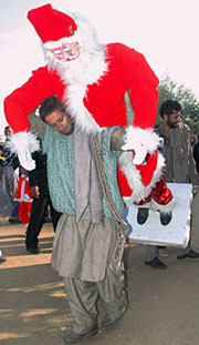 A worker carries a Santa Claus idol to be erected for the upcoming Christmas celebrations, in Jammu on Saturday.