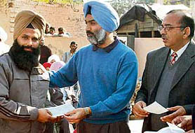 The PSIDC Vice-Chairman, Mr Deepinder Dhillon (centre), hands over a cheque of development grant to a village representative in Saidpura village on Monday.