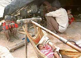 A baby lies unattended as his siblings and father concentrate on kitchen work in Ludhiana