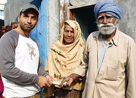 Mr Ramneet Singh, an NRI, hands over Rs 20,000 in cash to cart-puller Deewan Singh at his house in Bathinda on Sunday.