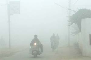 People drive their vehicles with headlights on as fog reduces visibility in Jalandhar on Monday