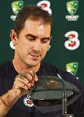 Australias Justin Langer picks up his baggy-green cap as he leaves a press conference after announcing his retirement in Sydney on Monday.