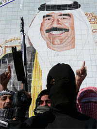 Armed Arab Sunni militants stand in front of a portrait of executed dictator Saddam Hussein in Al-Dawr, close to Saddam's home village Awja.