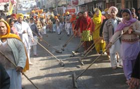 Devotees clean the road during the nagar kirtan to mark the birth anniversary of Guru Gobind Singh in Jalandhar on Wednesday