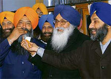 Mr Sukhbir Badal offers a ladoo to Mr Prem Singh Chandumajra on his return to the SAD in Chandigarh on Wednesday.