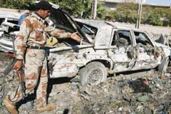 An Iraqi soldier inspects the scene of bomb attack in Baghdad 