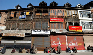 People sit in front of closed shops during a strike held to protest against the execution of Saddam Hussein, in Srinagar on Friday.