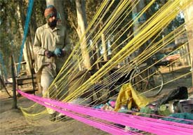Strings on air: A man winds up kite strings after strengthening with wax and glass shreds along a roadside in Jalandhar on Friday. 
