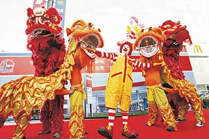 A lion dance troupe performs with Ronald McDonald at the opening of a McDonald's drive-thru outlet built next to a gas station in Beijing on Friday. US fast-food giant McDonald's, in cooperation with China's largest oil refiner Sinopec, will open two stores a week in China until 2008, with a focus on drive-in windows at gas stations to take advantage of the nation's auto industry.
