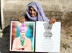 Brahmi Devi, widow of George Cross awardee Naik Kirpa Ram, with a picture of her husband at Bhapral village in Bilaspur district