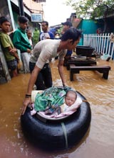 A resident evacuates a two-week-old baby from a flooded area in east Jakarta on Sunday