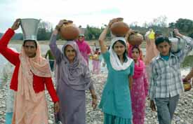 Villagers carry utensils filled with water from kunah khud in Nadaun to offer it at the adjoining Shiv temple to pray for rain