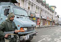 A security force jawan stands guard beside a vehicle in Srinagar on Sunday