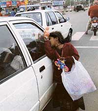 An underprivileged child tries to sell toys to a motorist to make both ends meet in an inclement weather at Mohali on Monday.