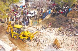 A bulldozer removing debris of the four-storeyed building that collapsed after heavy rain last night, killing eight persons at Madipur