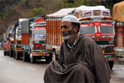 A driver sits on the road as trucks line up at Chanani after the Jammu-Srinagar National Highway was closed due to heavy rain and snowfall on Monday