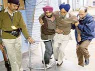 A voter being helped by relatives on the way to the polling booth at Kurali