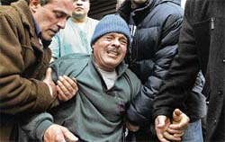 People help Fouad Attar as he mourns his dead son Micheal who was killed in a bomb blast in a village north of the Lebanese capital, Beirut, 