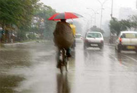 A cyclist tries to protect himself from rain in Ludhiana