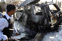 A policeman inspects a burnt police vehicle after a series of bomb attacks in Baghdad on Monday. The attack, which targeted a police patrol, killed six persons and injured 40 others