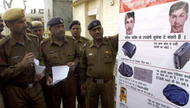 Police personnel look at the poster displaying the improved sketches of the suspects of Samjhauta Express train blasts in Panipat on Sunday