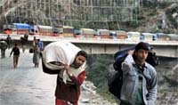 Passengers walk on foot to reach their destinations due to the closure of the Jammu-Srinagar National Highway near Khuni Nullah, about 170 km from Jammu, on Monday.
