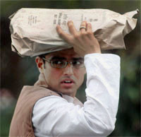 Congress MP Sachin Pilot holds a copy of the Budget to protect himself from rain at Parliament House In New Delhi