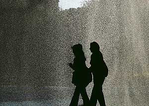 Two girls pass by waves of water springing from the fountain at Rose Garden in Chandigarh.
