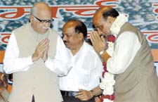 BJP president Raj Nath Singh and senior party leader L. K. Advani greet each other, while Delhi BJP president Harsh Vardhan looks on at the Parivartan Sabha