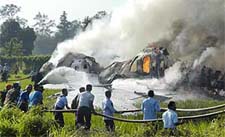 Rescue workers try to put out the flames of the burning fuselage of a Garuda Boeing 737-400 jet not long after it crashlanded at Yogyakarta airport on Wednesday. 