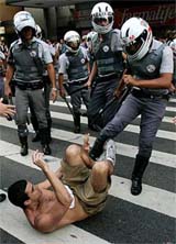 A policeman kicks a protester during a march against U.S. President George W. Bush in Sao Paulo on Thursday