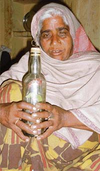 An old craftswoman peering at a bottle with a decorative structure inside