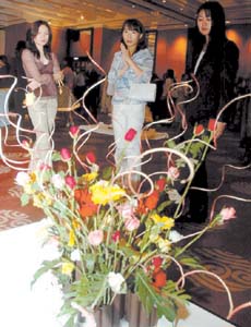 Foreign visitors admiring flowers at an exhibition, A Duet of Flowers