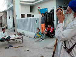 An old man prays outside his home following rumours of an earthquke in Patiala.