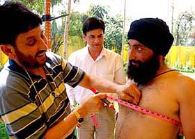 An official measures the chest of a candidate for the post of fireman during the physical test in Jammu