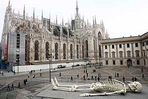 People look at a sculpture by Italian artist Gino De Dominicis placed near the Duomo cathedral in Milan on Friday. The 24-metre long skeleton will remain on display for one month.