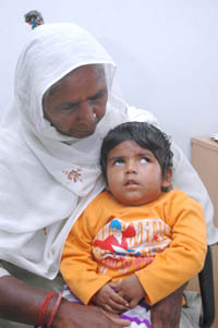 Two-year-old meningitis patient Sanju sits in his grandma's lap in Jalandhar on Thursday. 