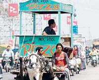 The frame of a pizza outlet is carried on a horsecart through the city as the owner seems to have changed his area of operations