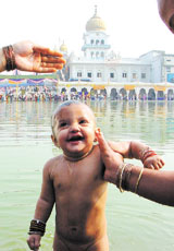 A child being given a holy dip at Gurdwara Bangla Sahib on the occasion of Baisakhi in the Capital