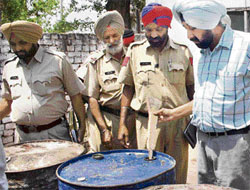 Police officials examine drums containing beef tallow and chemicals in Rajpura.