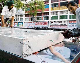 An illegal hoarding being removed from a liquor shop in a drive carried out by the estate office of the Chandigarh administration in Sector 22, Chandigarh, on Monday. Hoardings from over 100 shops were removed across the city during the drive.