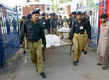Pakistani policemen carry the bodies of four brothers at a prison in Multan.