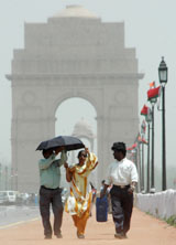 Visitors try to hold their umbrella in strong surface winds near India Gate in the Capital 