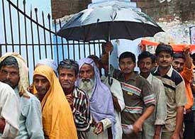Voters queue up during rain outside a polling booth during the third phase of assembly polls in Shahjahanpur, Uttar Pradesh, on Wednesday. 