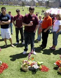 Virginia Tech junior Brian Skipper (centre) looks down at a memorial stone left adorned with flowers and other mementos honouring his faculty adviser, Prof G.V. Longanathan, on the Virginia Tech campus on Sunday.  AP/PTI photo