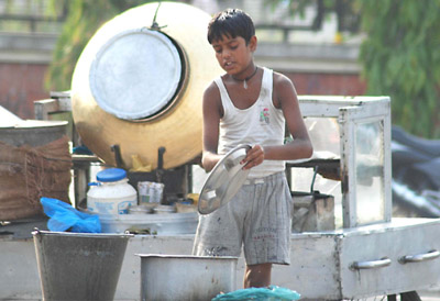 A child-labourer cleans utensils near district administrative complex in Jalandhar. 